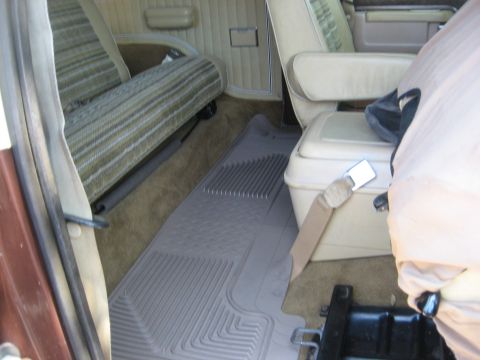 1979 Ford Bronco - Rear interior view of a 1979 Ford Bronco, striped upholstery and a center console with a seatbelt.