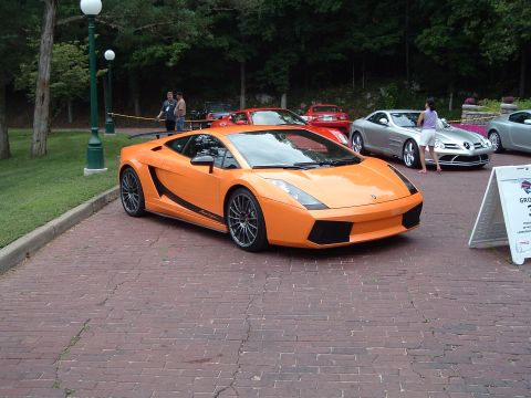 1999 Mercury Grand Marquis - An orange Lamborghini Gallardo is displayed with other luxury vehicles on a brick surface.