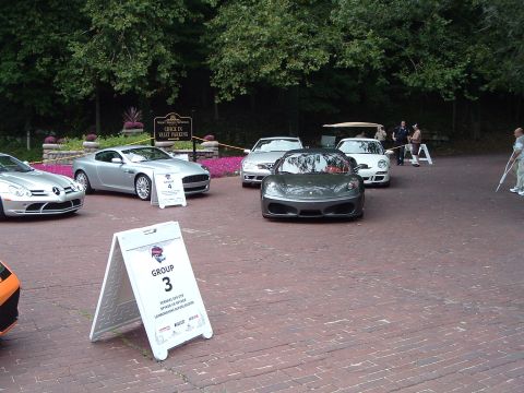 1999 Mercury Grand Marquis - A collection of high-end vehicles are gathered, with signs indicating group assignments for an event.