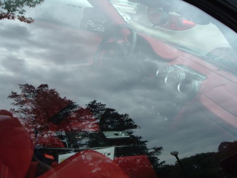 1999 Mercury Grand Marquis - Interior view of a red car, with reflections of the surrounding environment on the windshield.