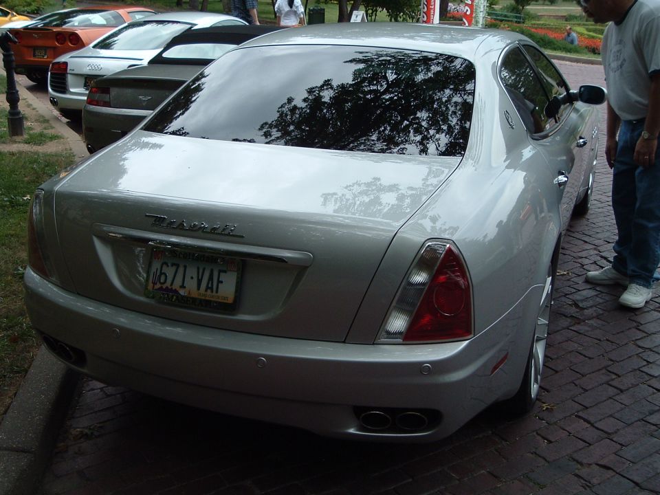 Rear view of a silver Maserati Quattroporte parked next to other cars