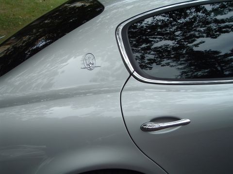 1999 Mercury Grand Marquis - A close-up view of the side of a silver Maserati, showing its distinctive emblem and door handle.
