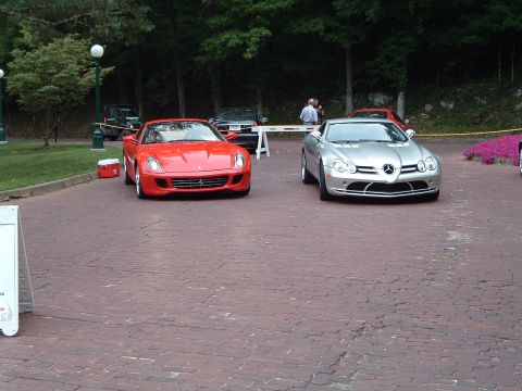 1999 Mercury Grand Marquis - Two exotic sports cars, a red Ferrari and a silver Mercedes-Benz SLR McLaren, are parked on a brick surface with trees in the background.