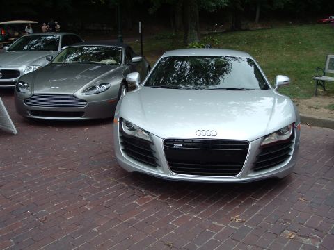 1999 Mercury Grand Marquis - Two luxury sports cars, an Audi R8 and an Aston Martin Vantage, are parked on a brick surface with trees in the background.