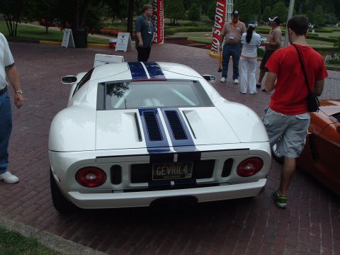 1999 Mercury Grand Marquis - This white Ford GT with racing stripes features a custom license plate and is parked on a brick surface.