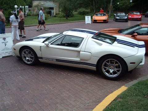 1999 Mercury Grand Marquis - A white Ford GT is displayed alongside other vehicles at an outdoor event.