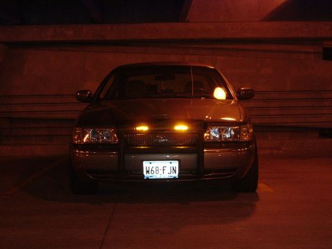 2003 Mercury Grand Marquis - A police car is parked at night, its emergency lights illuminated.