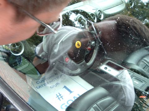 1999 Mercury Grand Marquis - The interior of a Ferrari shows its steering wheel, dashboard, and a sign indicating customer satisfaction is the top priority.