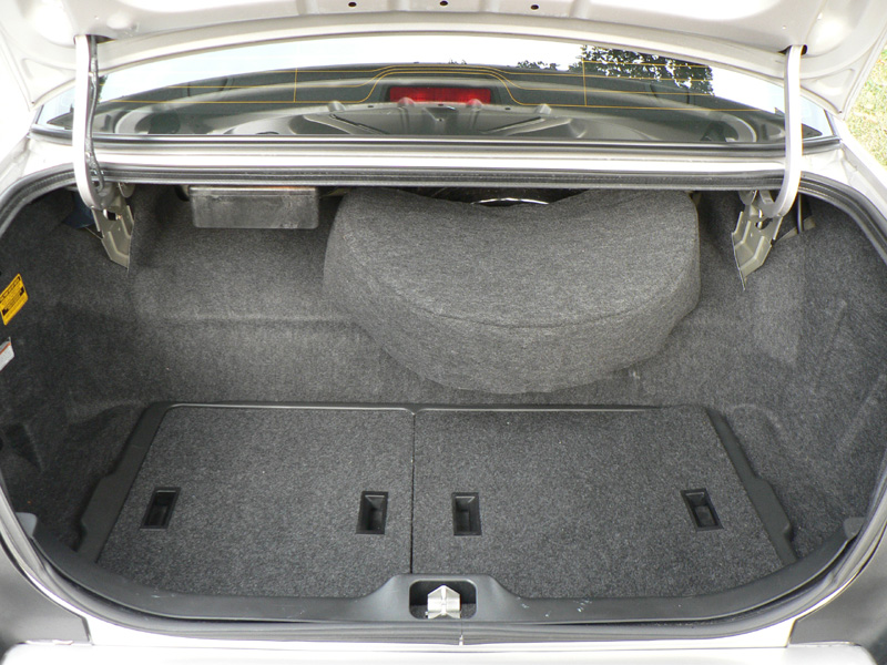 Open carpeted trunk of a sedan with spare tire hump and fold-down seats