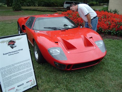 1999 Mercury Grand Marquis - A red Superformance GT40 rolling chassis is displayed on grass next to an informational sign.