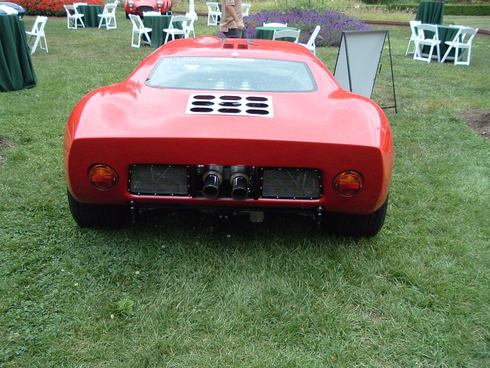 Red sports car rear with quad exhaust pipes and louvered engine cover