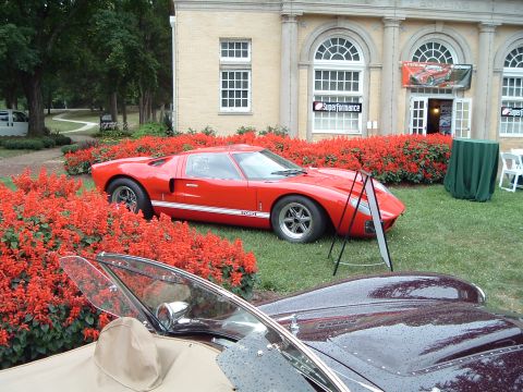 1999 Mercury Grand Marquis - A red sports car is displayed outdoors with red flowers and a building in the background.