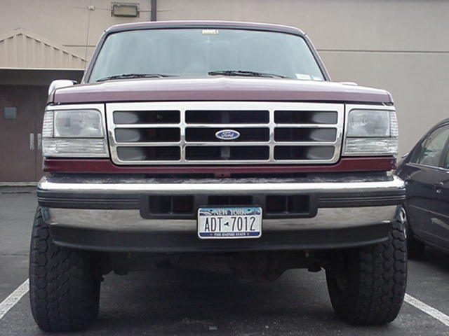 Front view of a maroon Ford F-150 pickup truck with a chrome grille and bumper. License plate reads ADT-7012