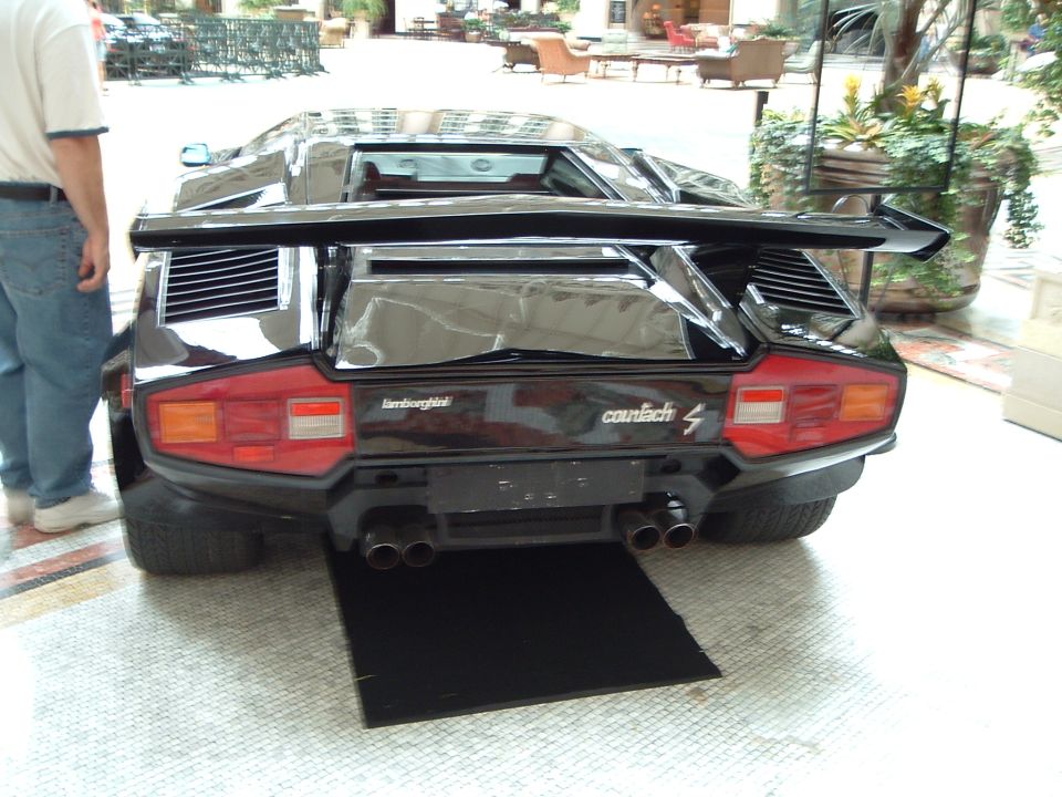 Black Lamborghini Countach rear view with large wing and quad exhaust pipes