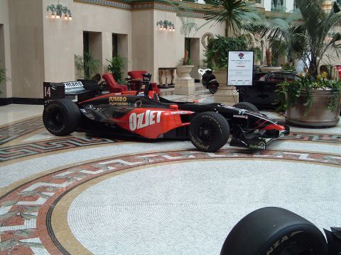 1999 Mercury Grand Marquis - A black and red racing car with "Ozjet" branding is displayed indoors.