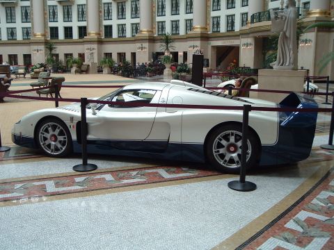 1999 Mercury Grand Marquis - A white and blue Maserati MC12 is displayed indoors, with a statue and seating in the background.
