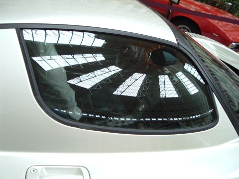 1999 Mercury Grand Marquis - Reflection of a building's glass roof seen in the rear window of a white car.