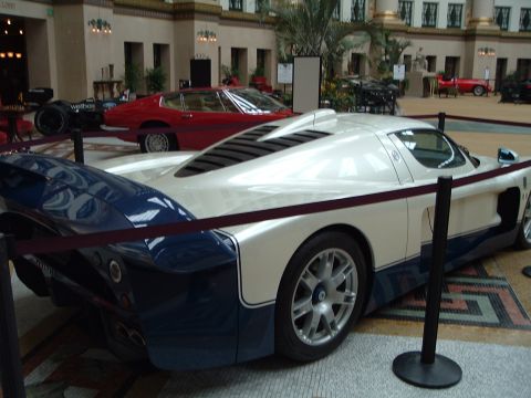1999 Mercury Grand Marquis - A white and blue Maserati MC12 is displayed indoors alongside other vehicles.