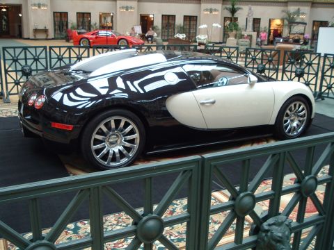 1999 Mercury Grand Marquis - A two-tone Bugatti Veyron is displayed indoors, with a red Ferrari visible in the background.