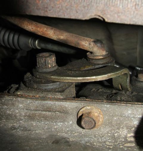 1985 Ford LTD Crown Victoria - Close-up view of a mechanical part on a vehicle's undercarriage, showing bolts and a rusty pipe.