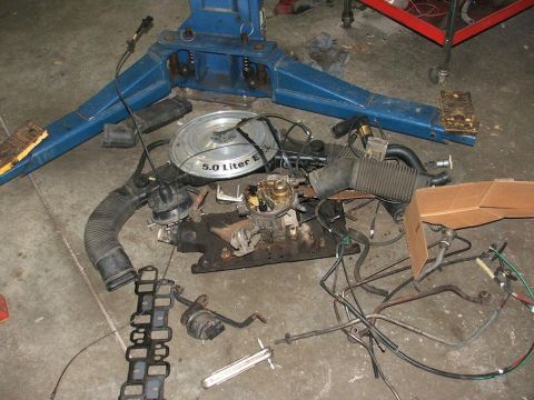 1985 Ford LTD Crown Victoria - Disassembled engine components are laid out on a concrete floor next to a vehicle lift.