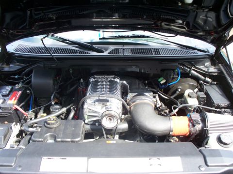 2007 Ford Mustang - Engine bay of a truck fitted with a polished Whipple twin-screw supercharger sitting atop the V8, plumbed through a black intercooler tube…