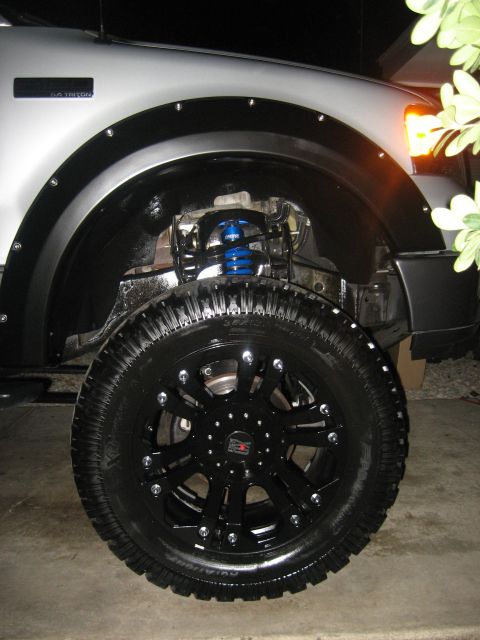 1979 Ford Bronco - Close-up of a truck's front wheel assembly, showing aftermarket modifications to the suspension and wheel.