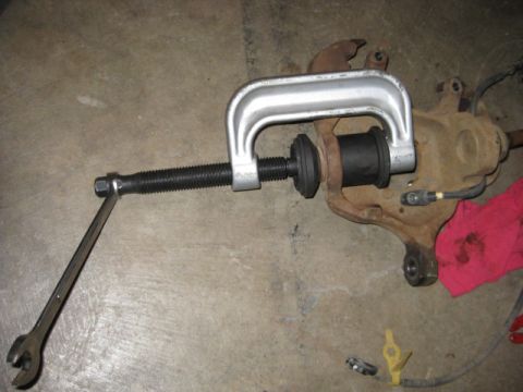 1995 Ford Bronco - A C-clamp style ball joint press tool is used on a suspension component, with a wrench attached to the screw mechanism.
