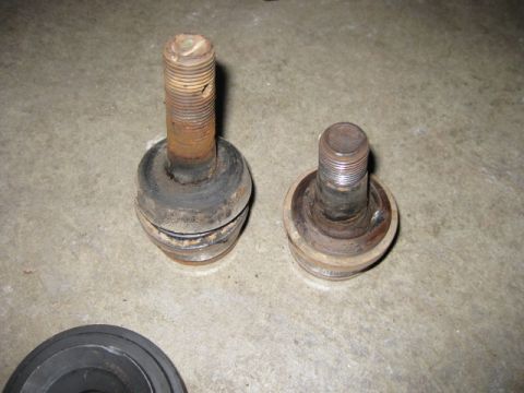 1995 Ford Bronco - Two ball joints are shown side-by-side on a concrete floor, likely for automotive repair.