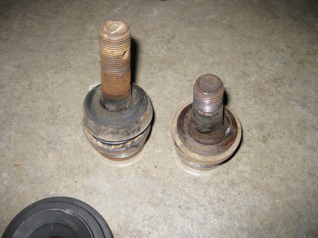 two ball joints, one larger than the other, resting on a concrete surface