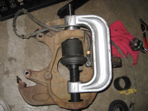 1995 Ford Bronco - A ball joint press tool is used on a rusty suspension component, likely for removal or installation.