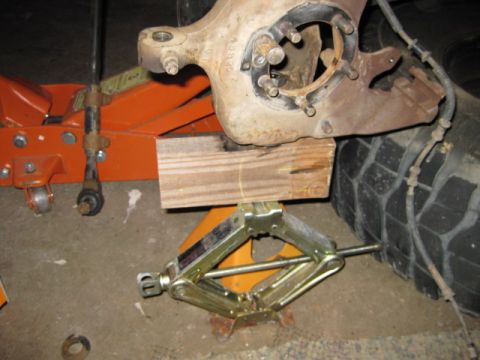 1995 Ford Bronco - Vehicle suspension components are supported by a jack and jack stand during maintenance.