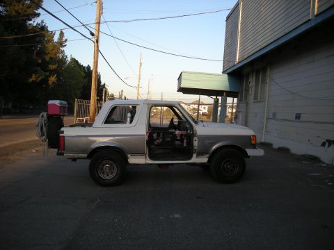 1991 Ford Bronco - This two-tone SUV is seen from the side with its doors open and a spare tire carrier mounted at the rear.