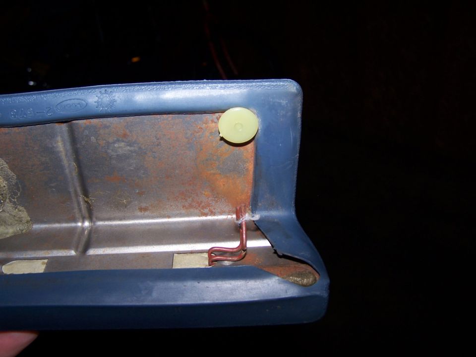 Close-up of a blue plastic trim piece with visible rust and a copper wire attached