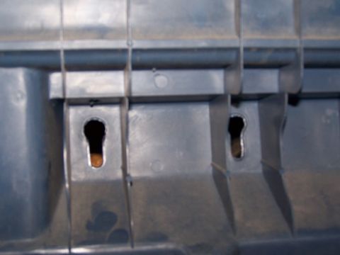 1986 Ford Bronco - This image shows a close-up of gray plastic trim with two keyhole-shaped slots for mounting.