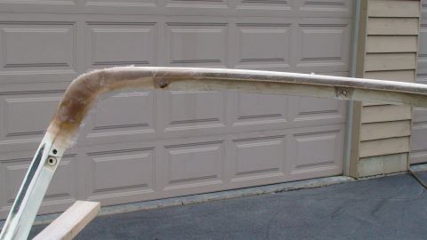 1979 Ford Bronco - A curved fiberglass roof support, possibly for a vehicle, is shown in front of a beige garage door.