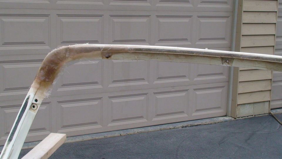 Fiberglass roof support with exposed fibers and metal mounting points, in front of a garage door