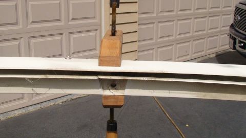 1979 Ford Bronco - A white metal beam is held by wooden clamps in front of a garage door, with a dark truck partially visible on the right.