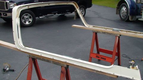 1979 Ford Bronco - A disassembled trim piece is supported by sawhorses outdoors, with vehicles visible behind it.