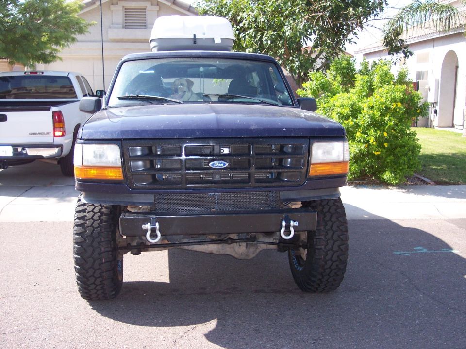 Lifted dark blue 1996 Ford Bronco front view with a white cargo box on roof.