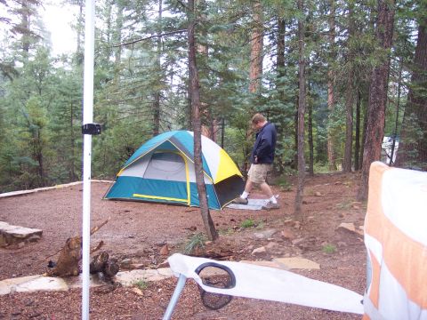 1996 Ford Bronco - A person stands next to a tent in a wooded campsite.