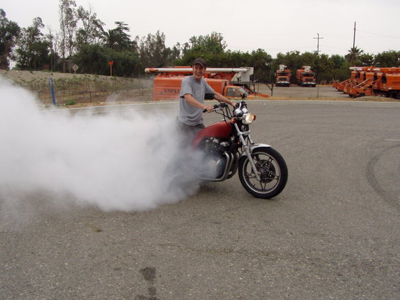 Man on a motorcycle doing a smoky burnout in a lot