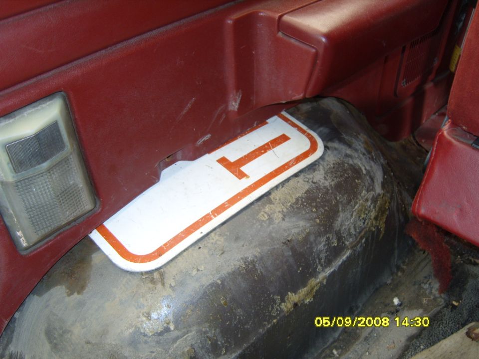 Rear wheel well of a red Ford truck with white and orange mud flap and side marker light