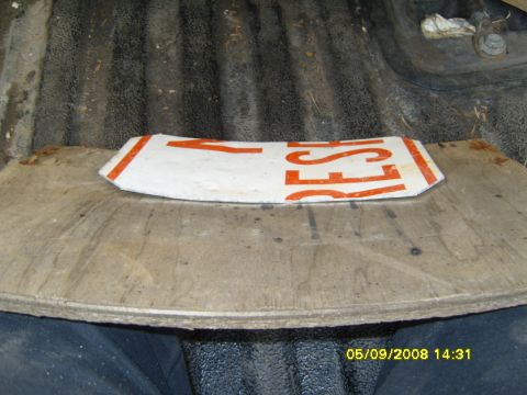 1989 Ford Bronco - A curved plywood template resting in a ribbed truck bed, with a white and orange lettered aluminum road sign cut down and clamped against i…
