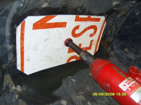 1989 Ford Bronco - A red 4-ton hydraulic porta-power ram with its threaded extension screw pressed against a cut white and orange aluminum sign panel, using i…