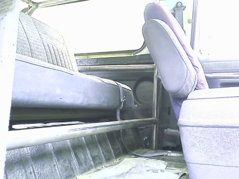 1990 Ford Bronco - The interior of a vehicle shows the rear bench seat and the back of a front seat. A roll cage is visible in the foreground.