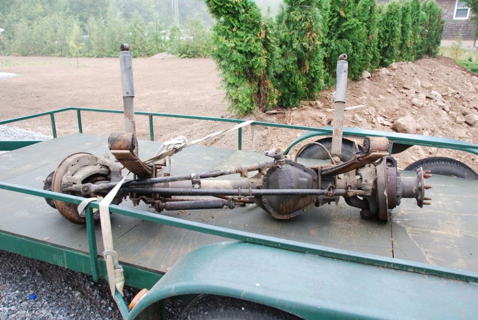 Removed solid front axle assembly strapped on a utility trailer