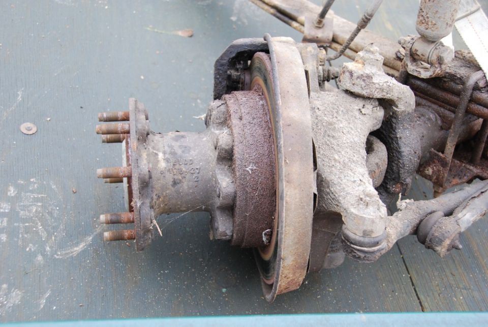 Rusty wheel hub, brake rotor and steering knuckle on the ground