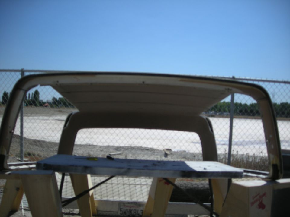 Interior view of a vehicle's headliner and roof structure, outdoors.