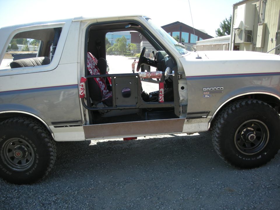 1991 Ford Bronco with driver's door removed, showing interior and roll cage